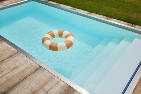 Piscina rettangolare con acqua blu chiara, bordo in legno e salvagente a Unbrick One lodge nei Paesi Bassi.