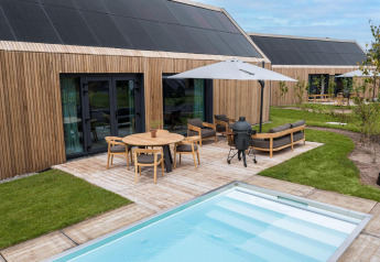 Lodge moderno de madera en Brinckerduyn, Países Bajos, con terraza, piscina, muebles de jardín y paneles solares.