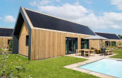 Moderne lodge ved Unbrick One med træbeklædning, solpaneler, terrasse, pool og grøn have i Brinckerduyn, Holland.