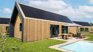 Moderne lodge ved Unbrick One med træbeklædning, solpaneler, terrasse, pool og grøn have i Brinckerduyn, Holland.