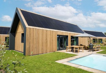 Lodge Unbrick One moderno a Brinckerduyn, Paesi Bassi, con facciata in legno, pannelli solari, patio e piscina.