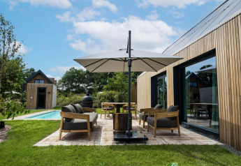Zona exterior en Unbrick One Lodge en Brinckerduyn, Países Bajos, con piscina, terraza y muebles modernos.