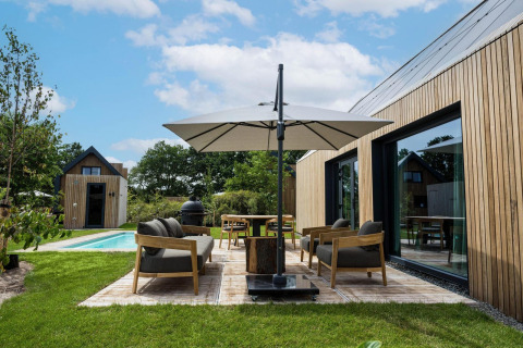 Buitenruimte van Unbrick One Lodge in Brinckerduyn, Nederland, met zwembad, terras en moderne zitplaatsen.