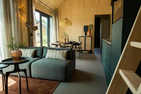 Sala de estar y comedor modernos en la Unbrick One Lodge con vista exterior en Brinckerduyn, Países Bajos.