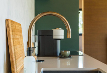 Moderne køkkenvask med messinghane, skærebræt og kaffemaskine på Unbrick One lodge i Brinckerduyn, Holland.