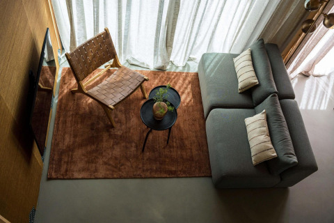 Stijlvolle zithoek in Unbrick One lodge met grijze sofa, stoel, tafel en daglicht bij Brinckerduyn.