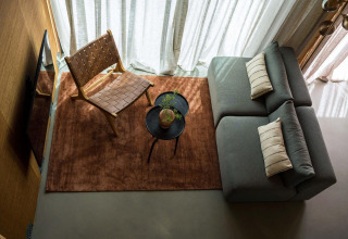 Stilfuld stue på Unbrick One lodge med gråt sofa, lænestol, sofabord og naturligt lys i Brinckerduyn.