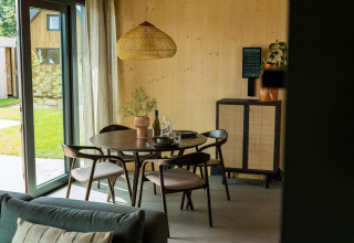 Moderne spiseplads ved store vinduer i Unbrick One-lodgen på Brinckerduyn, Holland, med naturudsigt.