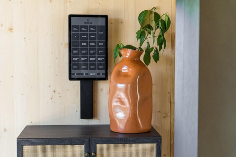 Un panel de control negro Unbrick montado en la pared cerca de un jarrón naranja y una planta verde en Brinckerduyn.