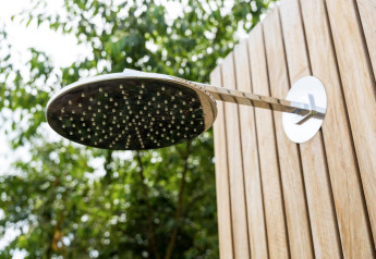Pommeau de douche extérieur fixé à un mur en bois devant des arbres à Brinckerduyn aux Pays-Bas.