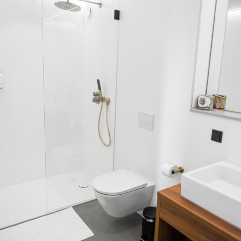 Baño moderno con inodoro suspendido, ducha de lluvia y lavabo de madera en Unbrick One lodge, Países Bajos.