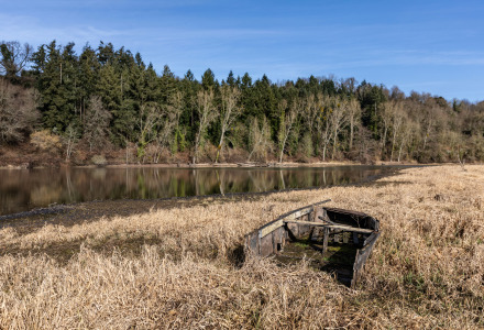 Abandoned boat on dry grass by a riverbank near Saint Julien des Landes, Pays de la Loire, France.