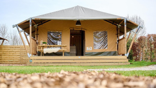 Safari tent Cottage at Camping Vossenberg in the Netherlands, shown from the front with a wooden porch.