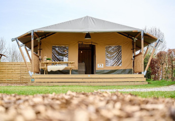 Tienda Safari Cottage en Camping Vossenberg, Países Bajos, vista desde el frente con porche de madera.