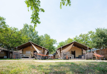 Safari-Zelte bei Villatent Outback im Bi Village, Kroatien, mit Bäumen und Hängematten im Vordergrund.