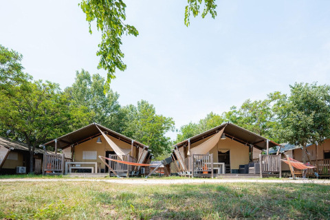 Tiendas safari en Villatent Outback en Bi Village, Croacia, rodeadas de árboles y con hamacas al exterior.