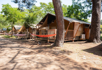 Safaritenten met houten veranda's en hangmatten bij Villatent Outback in Bi Village, Kroatië, tussen bomen.