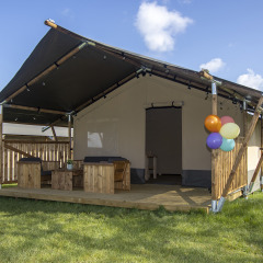 Cabaña de tienda safari de lujo con terraza de madera y globos en Camping Catsop, Limburg, Países Bajos.