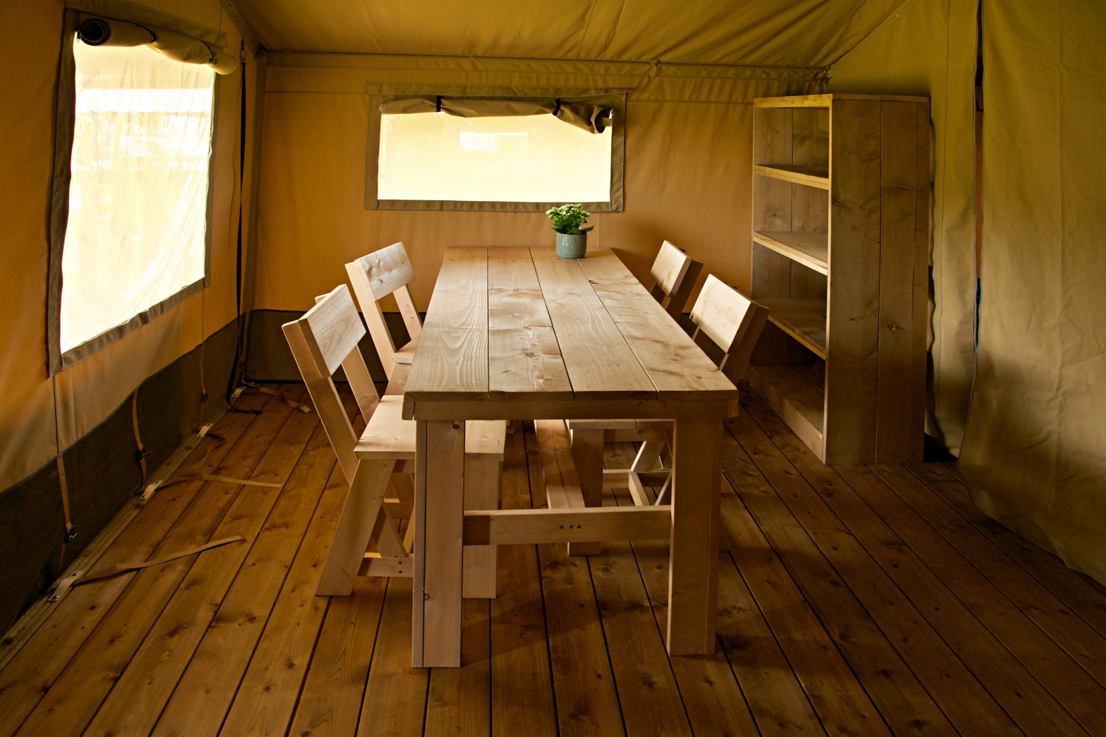 Binnenkant van een safaritent bij Rosenvold Strand Camping in Denemarken met houten tafel en stoelen.