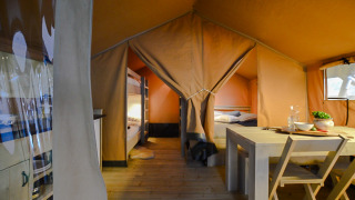 Indvendigt billede af et safaritelts luksuriøse interiør med køjesenge, spisebord og hyggelig stemning.