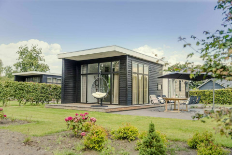 Moderna cabaña con ventanales y terraza en Vakantiepark Hölte, Países Bajos, rodeada de jardín.