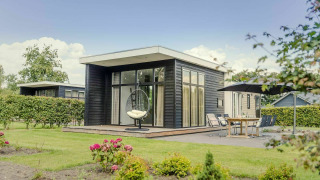 Modern lodge with large windows, patio seating, and garden at Vakantiepark Hölte in the Netherlands.