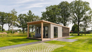 Panorama Lodge + Wellness mikrohus på Vakantiepark Hölte i Holland, omgivet af grønt græs og træer.