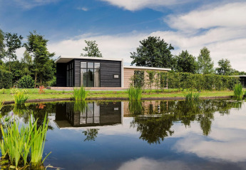 Lodge moderno con vasca idromassaggio presso un laghetto al Vakantiepark Hölte, Paesi Bassi, immerso nel verde.