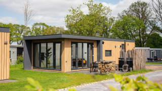Moderna Oak Lodge con vasca idromassaggio al Vakantiepark Hölte nei Paesi Bassi, immersa nel verde.