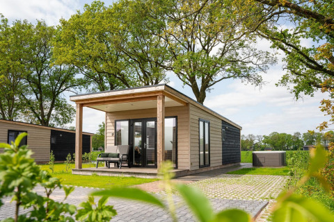Panorama lodge with wellness and jacuzzi at Vakantiepark Hölte in the Netherlands, surrounded by greenery.