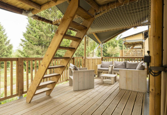 Terrazza in legno con posti a sedere e scala nella tenda Safari Ranger Lodge a Petite Suisse, Belgio.