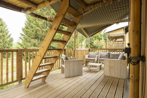 Wooden terrace with seating and staircase in the Ranger Lodge safari tent at Petite Suisse in Belgium.