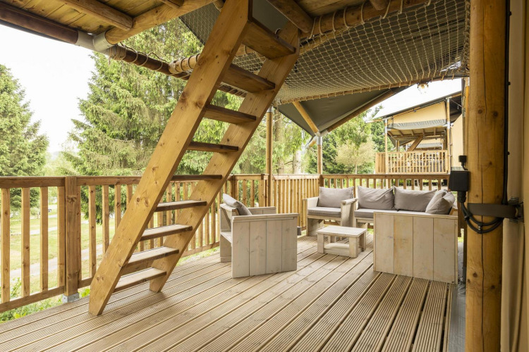 Terraza de madera con asientos y escalera en la tienda safari Ranger Lodge en Petite Suisse, Bélgica.