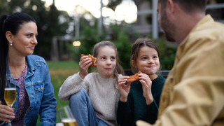 Dos hijas comen schnitzel mientras los padres disfrutan de una cerveza