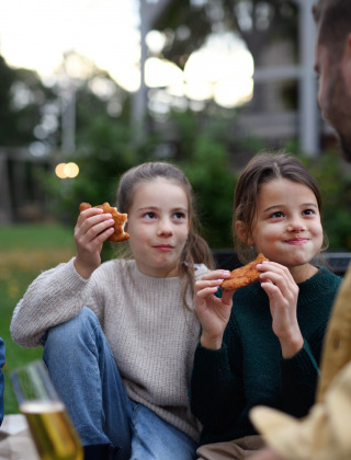 Dos hijas comen schnitzel mientras los padres disfrutan de una cerveza