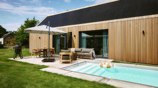 Lodge moderno Unbrick One en De Weelderik, Países Bajos, con piscina, terraza, fachada de madera y muebles al aire libre.