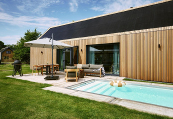 Moderno lodge Unbrick One a De Weelderik, Paesi Bassi, con piscina, terrazza, facciata in legno e arredo esterno.