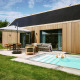 Moderne lodge ved De Weelderik i Nederlandene med træfacade, pool, terrasse og afslappende udendørs møbler.