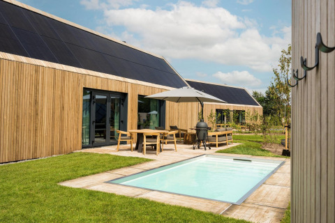 Lodge moderno con esterno in legno, piscina, pannelli solari e patio a De Weelderik nei Paesi Bassi.