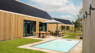 Lodge moderno con exterior de madera, piscina, paneles solares y terraza en De Weelderik, Países Bajos.