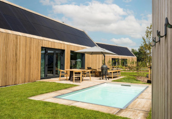 Lodge moderno con esterno in legno, piscina, pannelli solari e patio a De Weelderik nei Paesi Bassi.