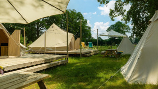 Outdoor view of the Happy teepee tent in the meadow at Holiday Park Mölke, Netherlands, with deck and benches.