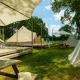 Udendørsbillede af tipi-teltet Happy på eng i Holiday Park Mölke, Holland, med træterrasse og borde.