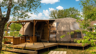Riverdome lodge con terraza y zona de estar en Holiday Park Mölke, Países Bajos, rodeado de naturaleza.