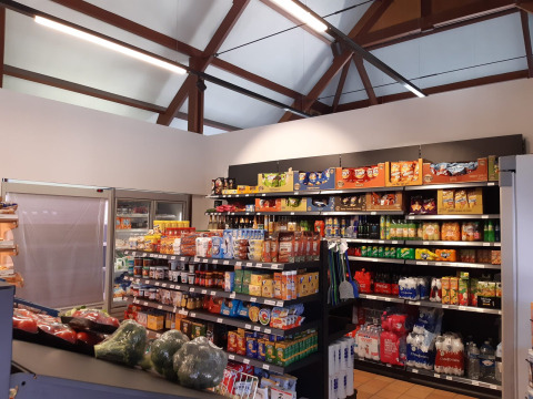 Een supermarkt in Kompas Camping Westende, West-Vlaanderen, met snacks, drank en groenten op de rekken.