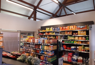 Een supermarkt in Kompas Camping Westende, West-Vlaanderen, met snacks, drank en groenten op de rekken.