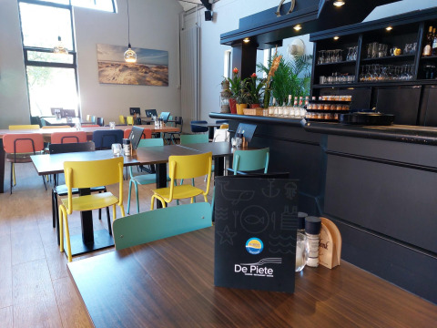 Interieur van het restaurant De Piete op Kompas Camping Westende met kleurrijke stoelen en tafels.