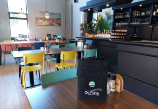Interieur van het restaurant De Piete op Kompas Camping Westende met kleurrijke stoelen en tafels.
