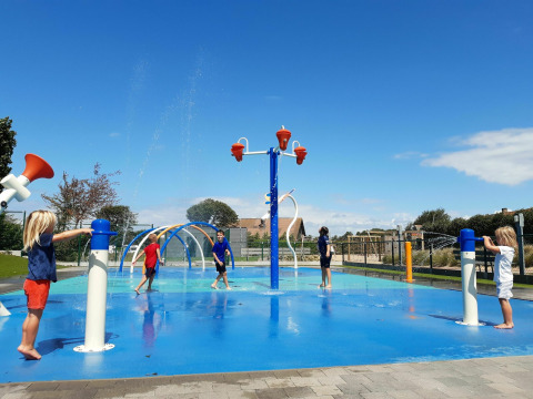 Kinderen spelen in een waterpark met fonteinen en waterstralen bij Kompas Camping Westende, West-Vlaanderen.