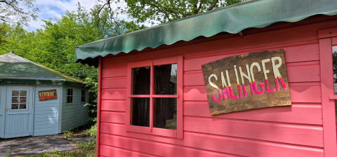 Twee kleurrijke houten huisjes bij vakantiepark Zomerlicht in Overijssel, Nederland, met Salinger- en Kerouac-bord.
